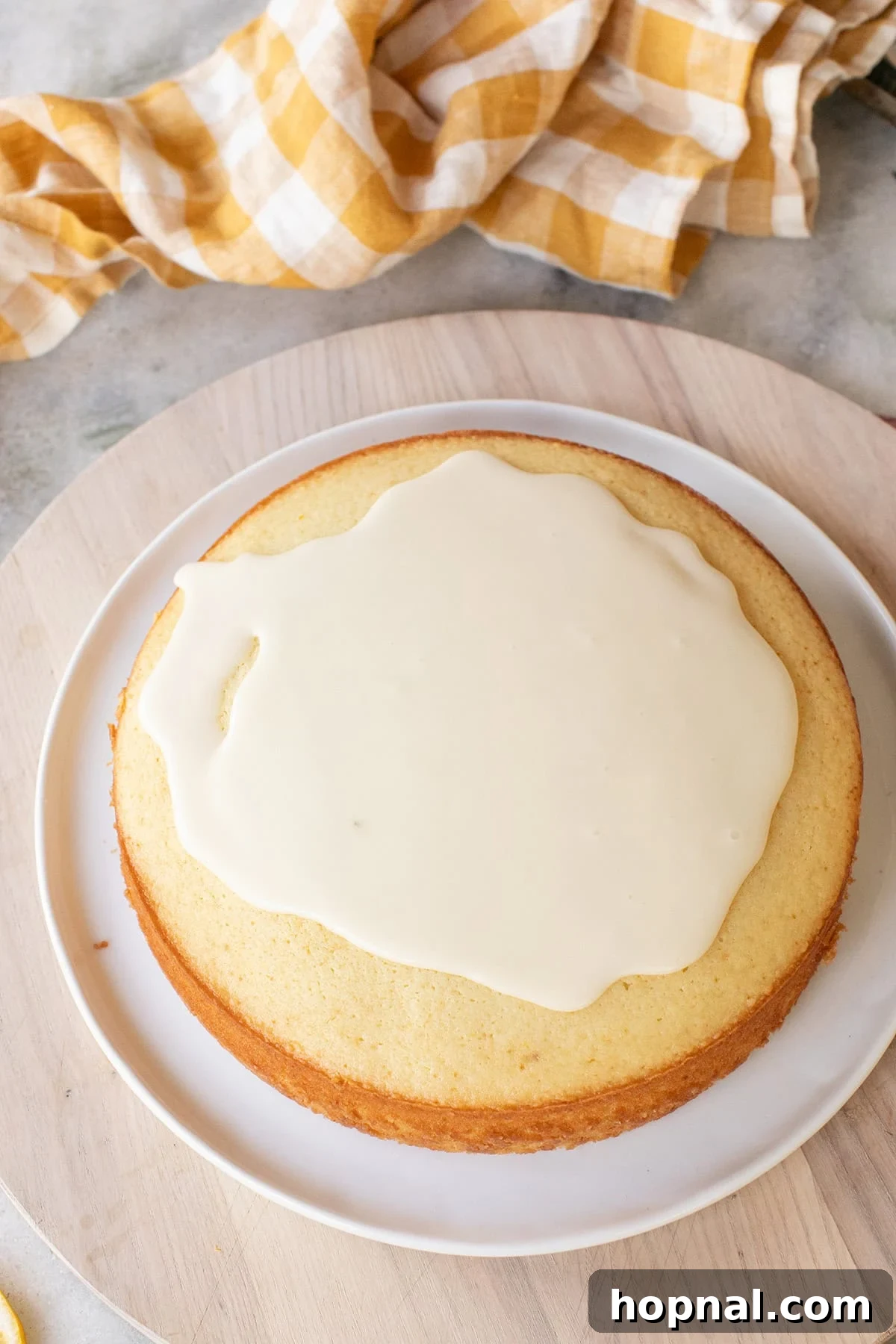 Pouring lemon olive glaze over a moist 9" round lemon cake.