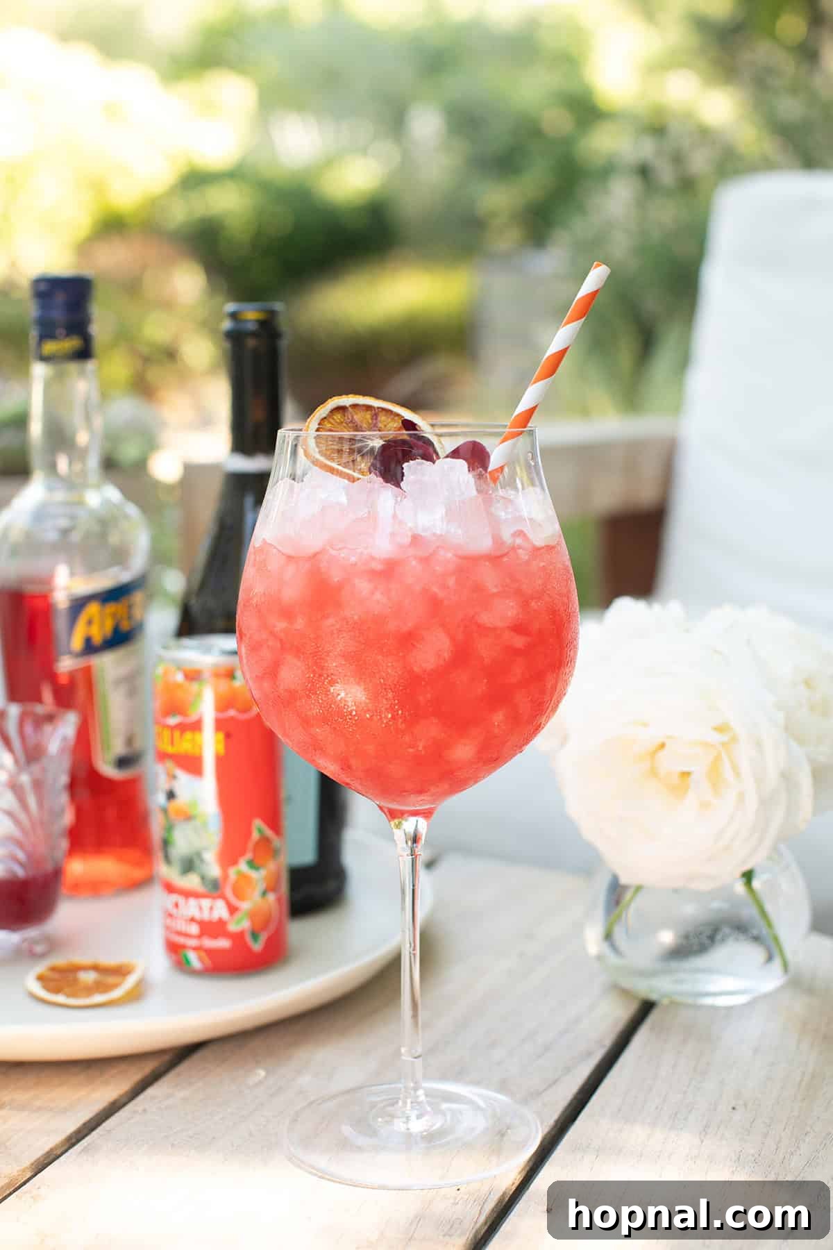 Blood orange spritz recipe in a large wine glass filled with ice.