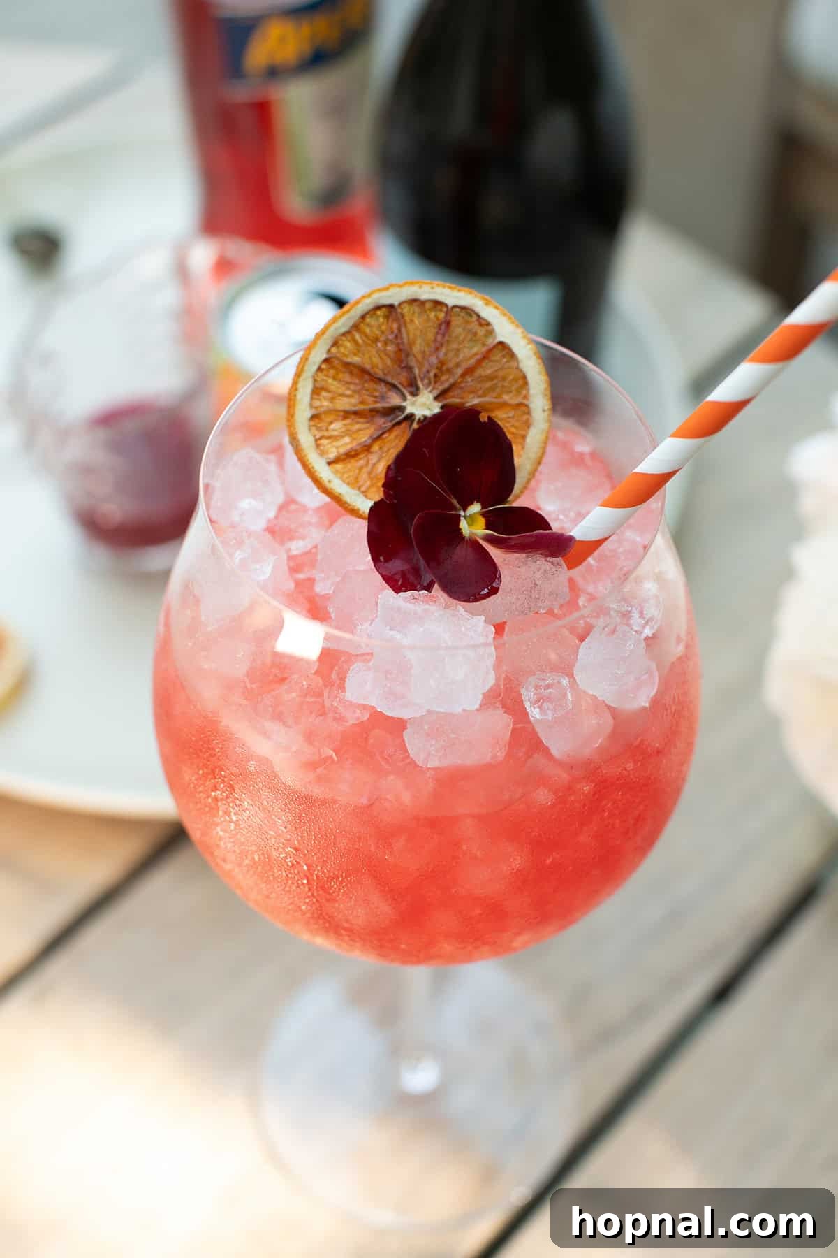Blood orange spritz in a large wine glass with crushed ice and a blood orange slice garnish.