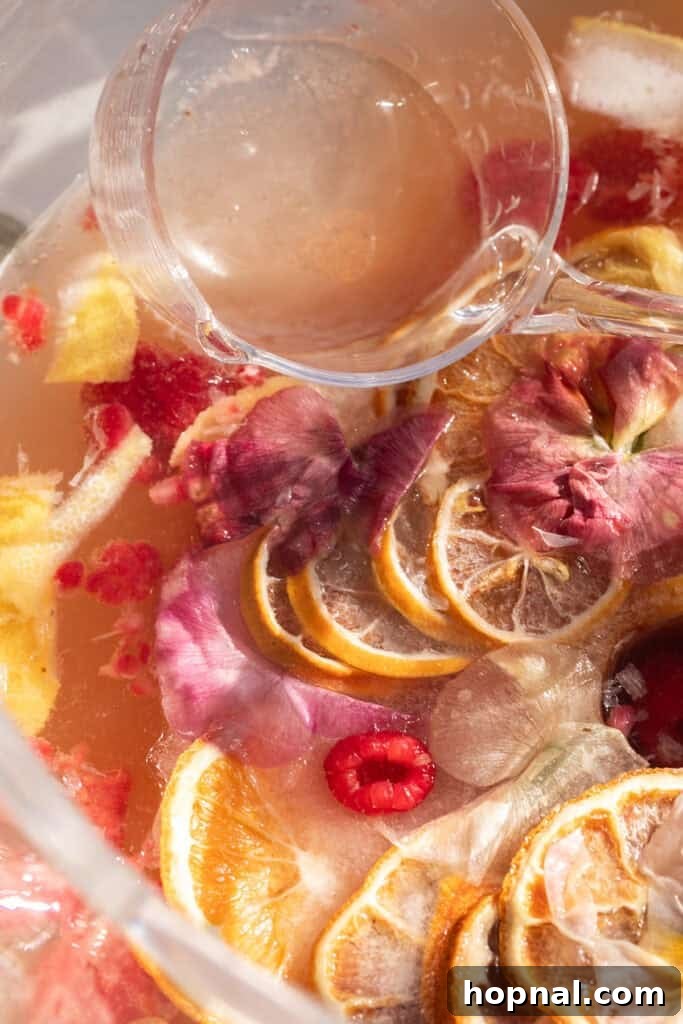 A beautiful champagne party punch, garnished with delicate edible flowers, served in an elegant punch bowl.